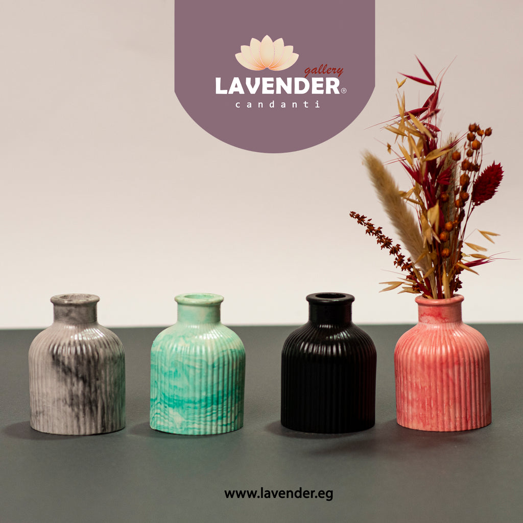 Four ceramic vases in different colors with a decorative plant