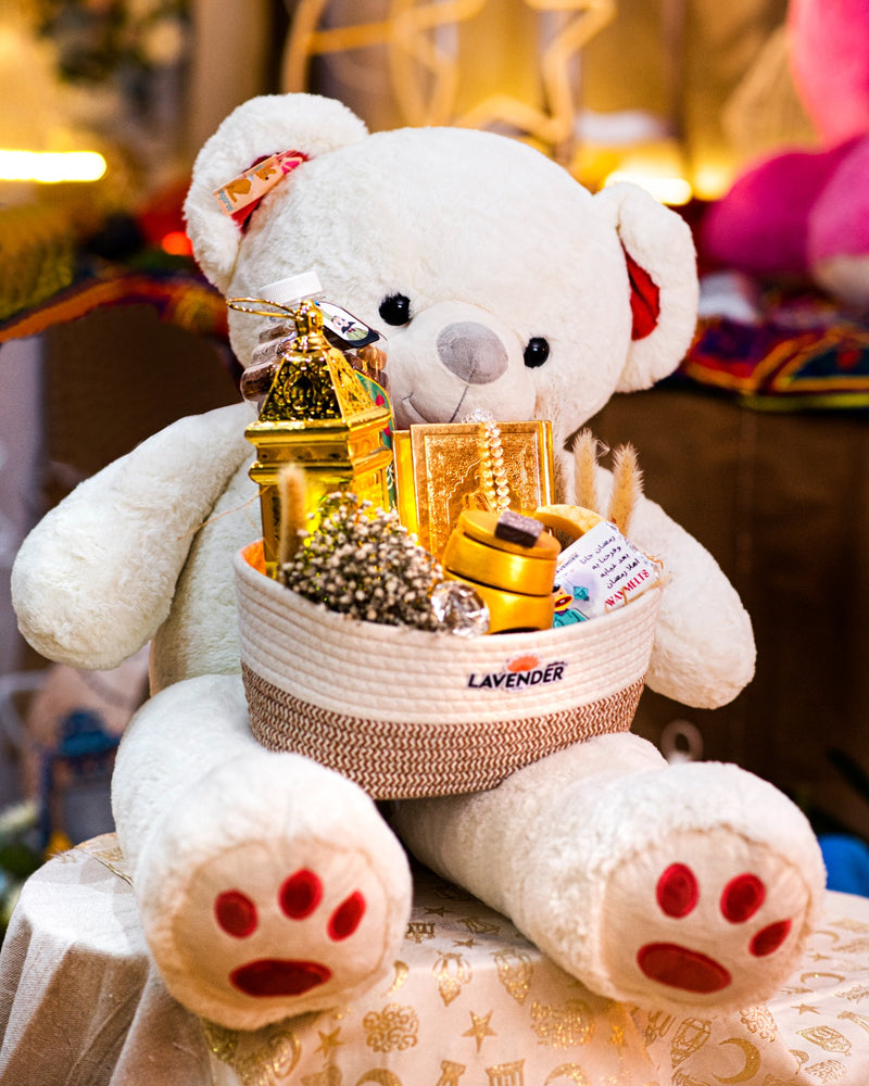 White teddy bear with a basket of gifts on a blurred background