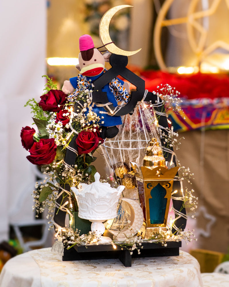 Decorative scene with a monkey figurine, flowers, and a lantern on a table.