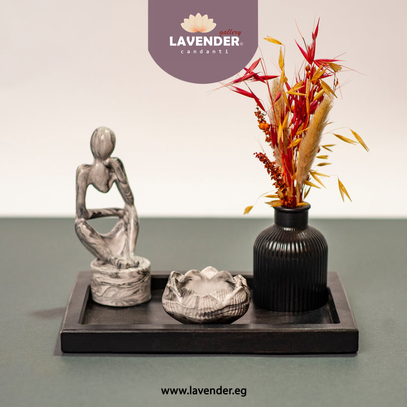 Decorative items including a sculpture, vase with flowers, and shell on a tray 